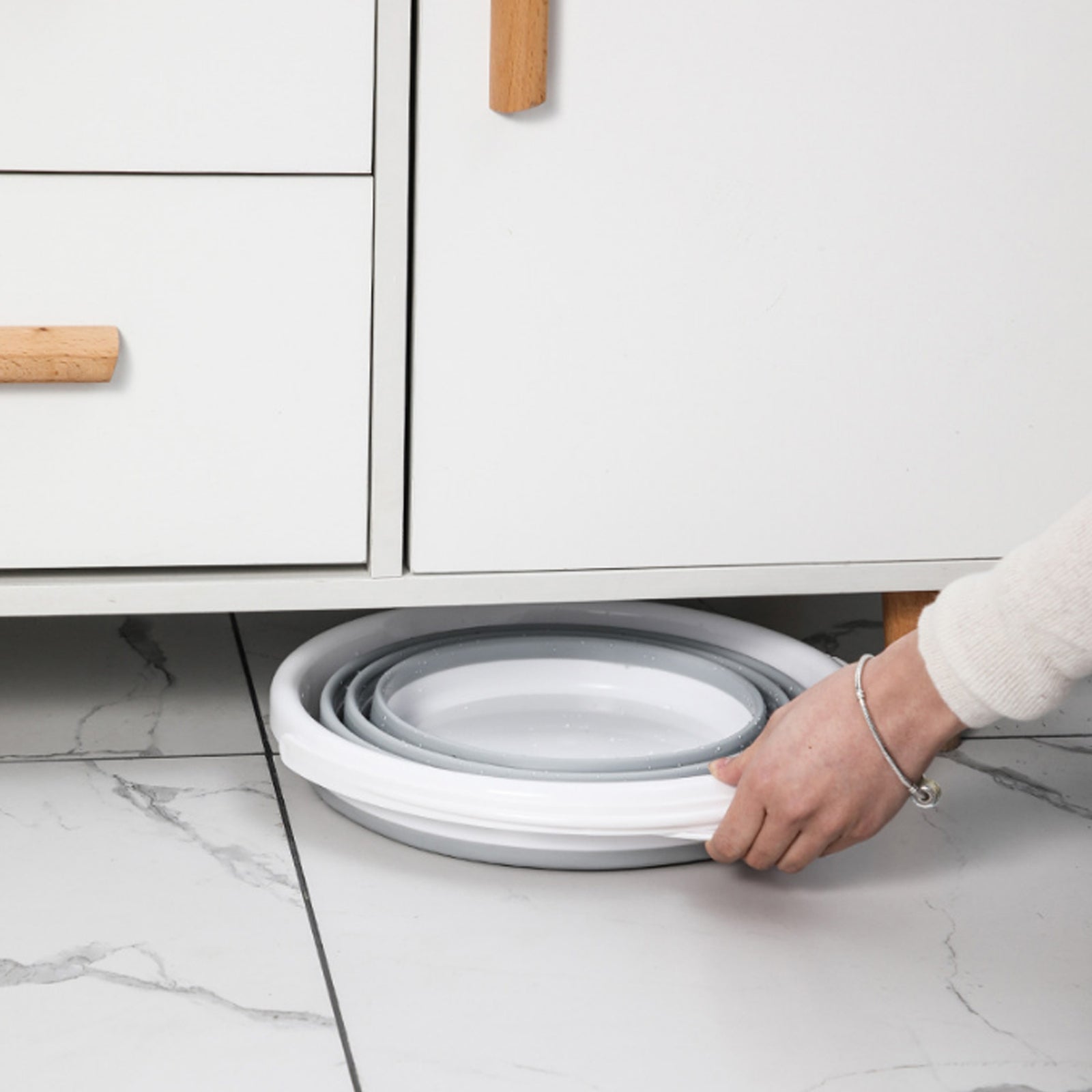 Person placing a stack of gray silicone coasters into a cabinet.