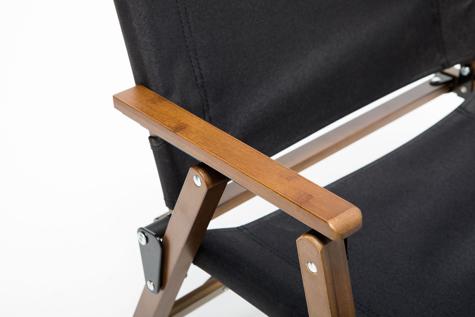 Close-up of a folding chair with black fabric and wooden armrest on a white background