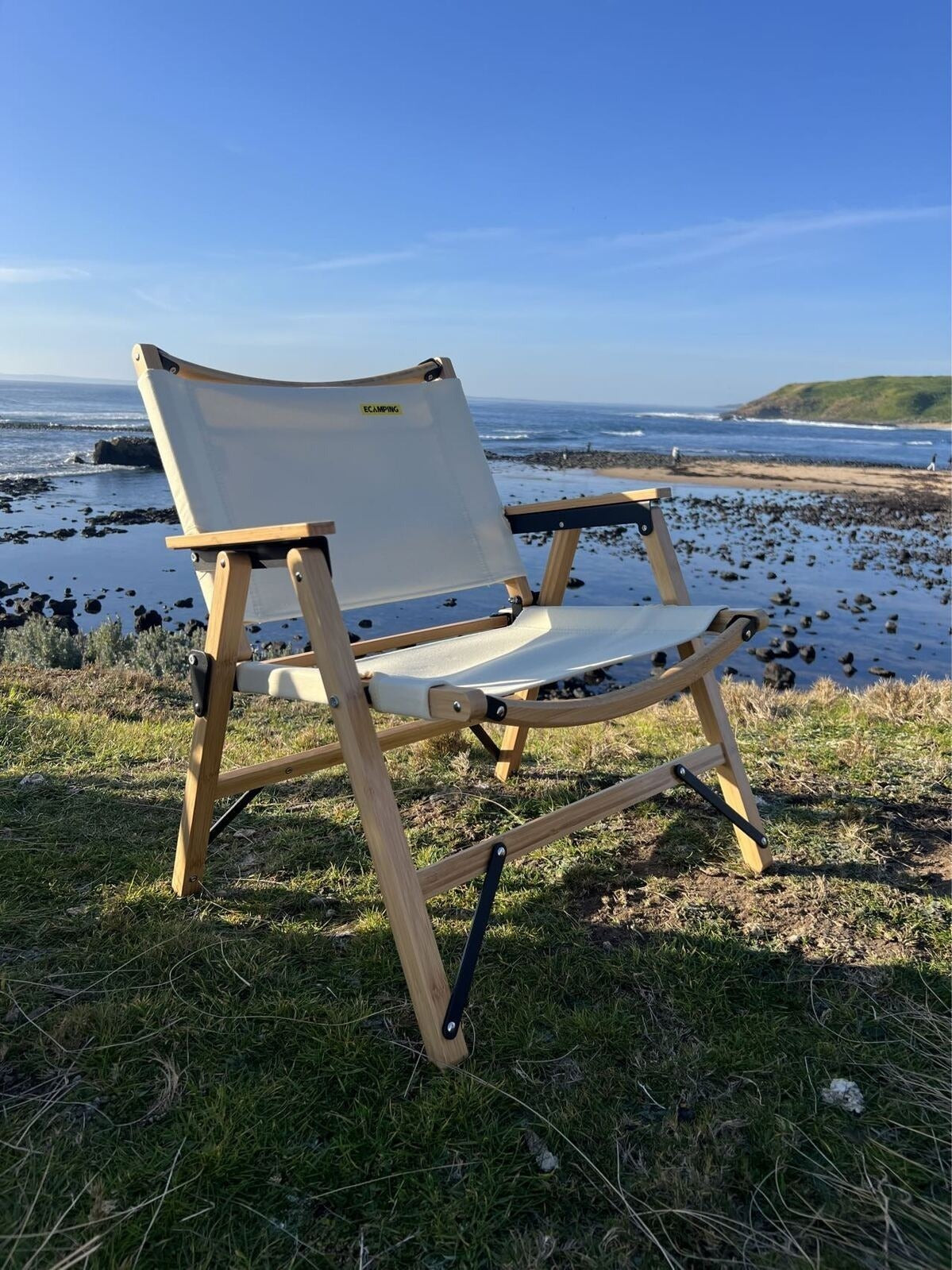 Foldable chair on a grassy area with a beach and ocean in the background
