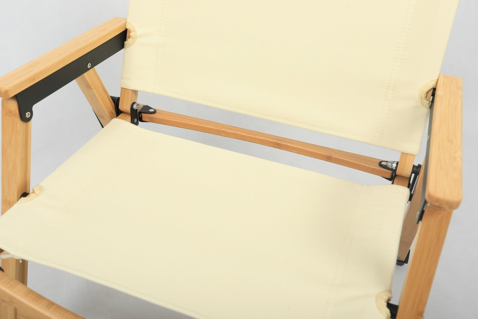 Wooden director's chair with beige canvas seat and backrest on a light gray background