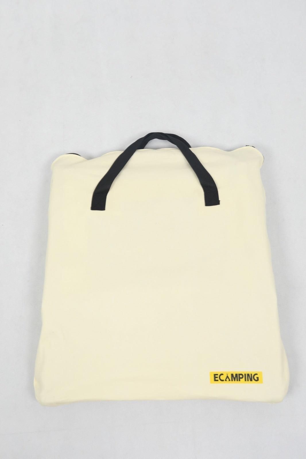 Folded yellow camping blanket with black handle on a light gray background