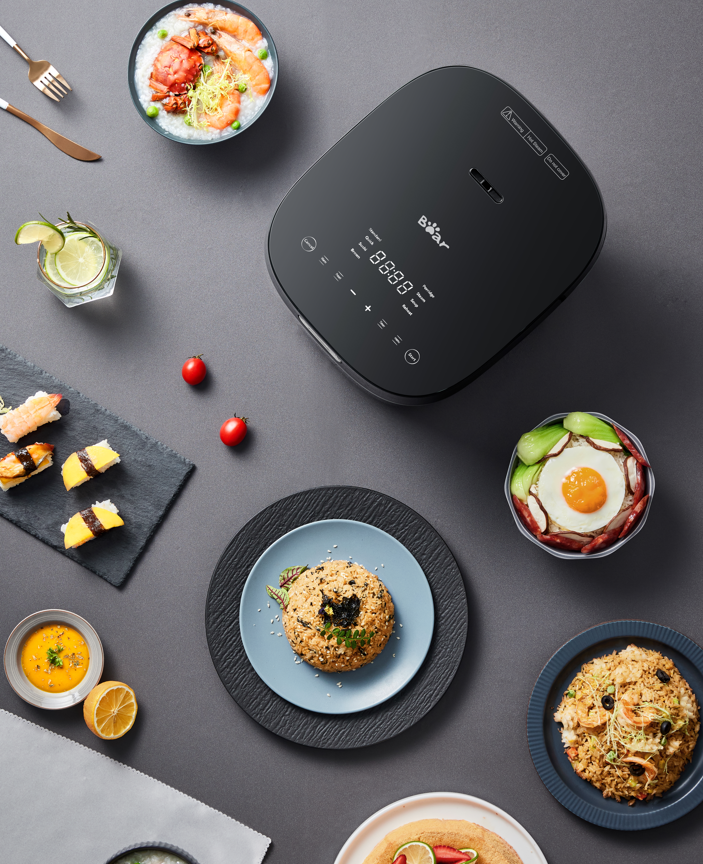 Smart rice cooker with various dishes on a gray surface