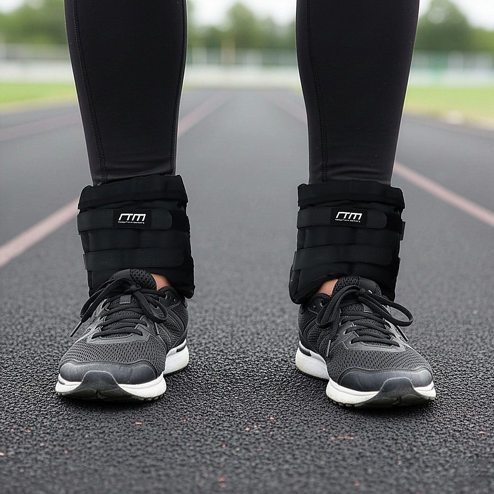 Person wearing black ankle weights on a running track