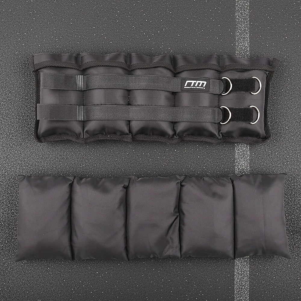 Black ankle weight pad with straps on a gray surface