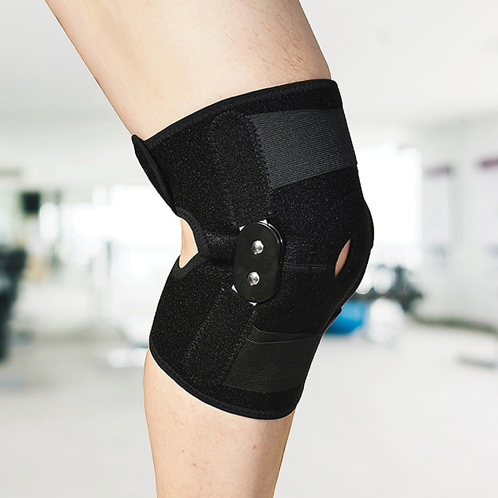 Black knee brace on a person's knee with a blurred indoor background