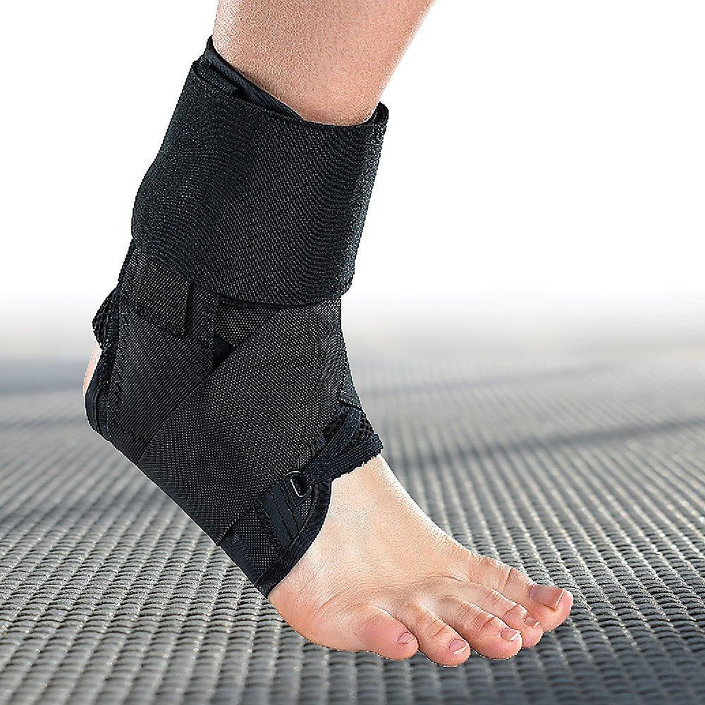 Black ankle support brace on a foot against a neutral background