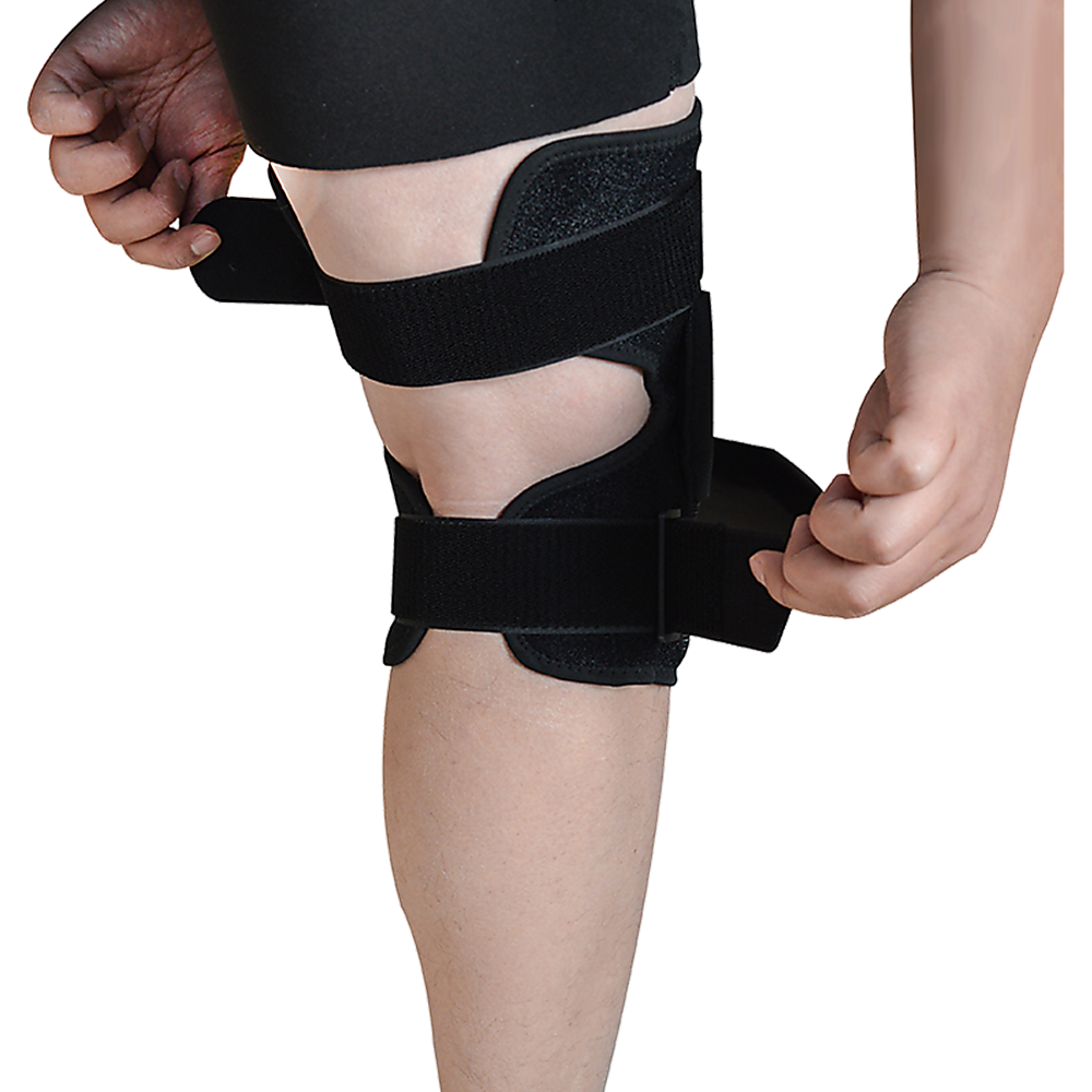 Black knee brace being worn on a person's leg against a white background