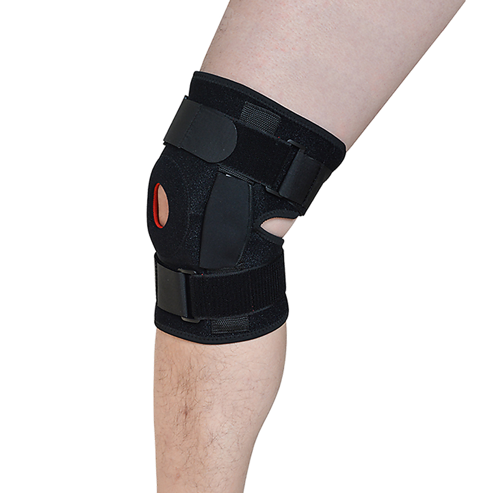 Black knee brace on a person's knee with a white background