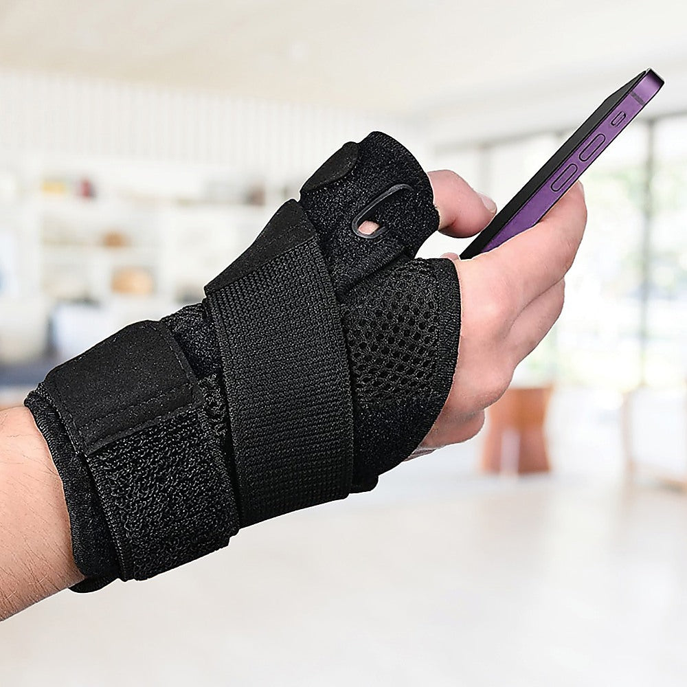 Hand wearing a black wrist support brace holding a smartphone.