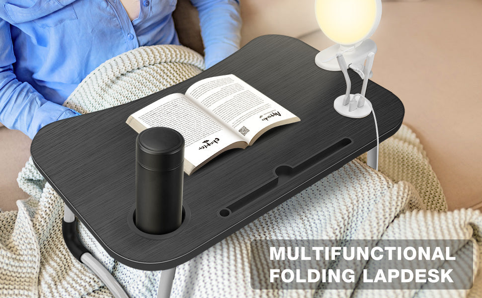 Multifunctional folding lap desk with book and cup on a couch