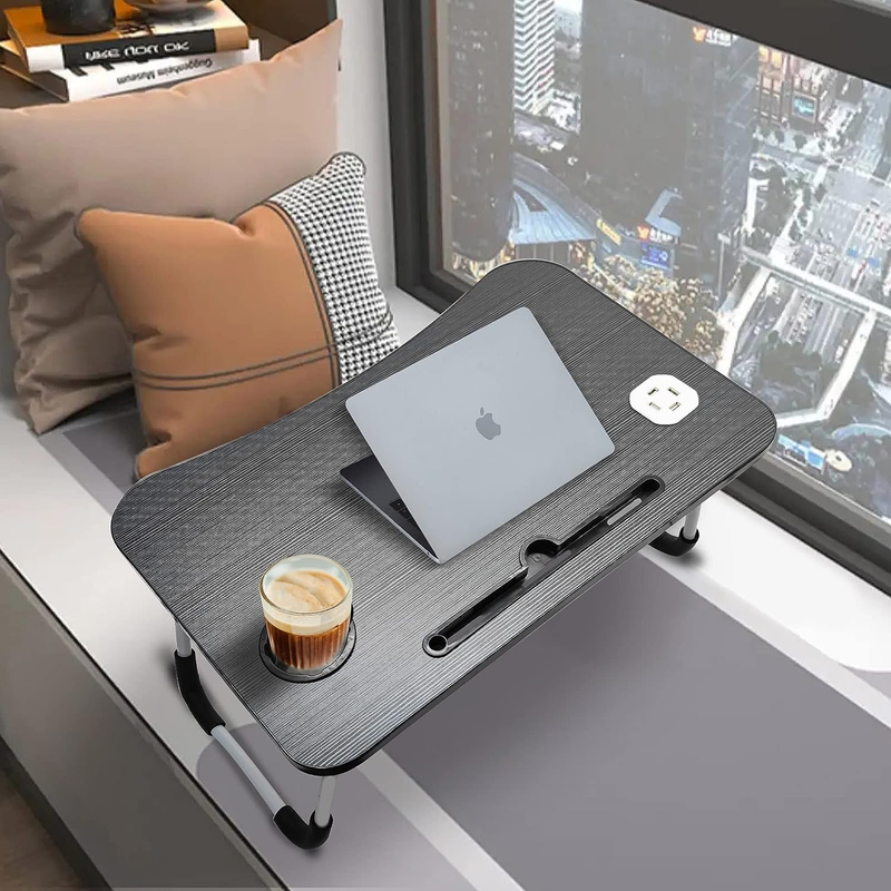 Laptop on a portable desk with a cup of coffee by a window with a cityscape view