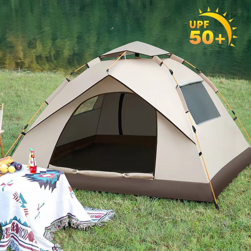 Beige camping tent with UPF 50+ sun protection feature in a grassy area near water.