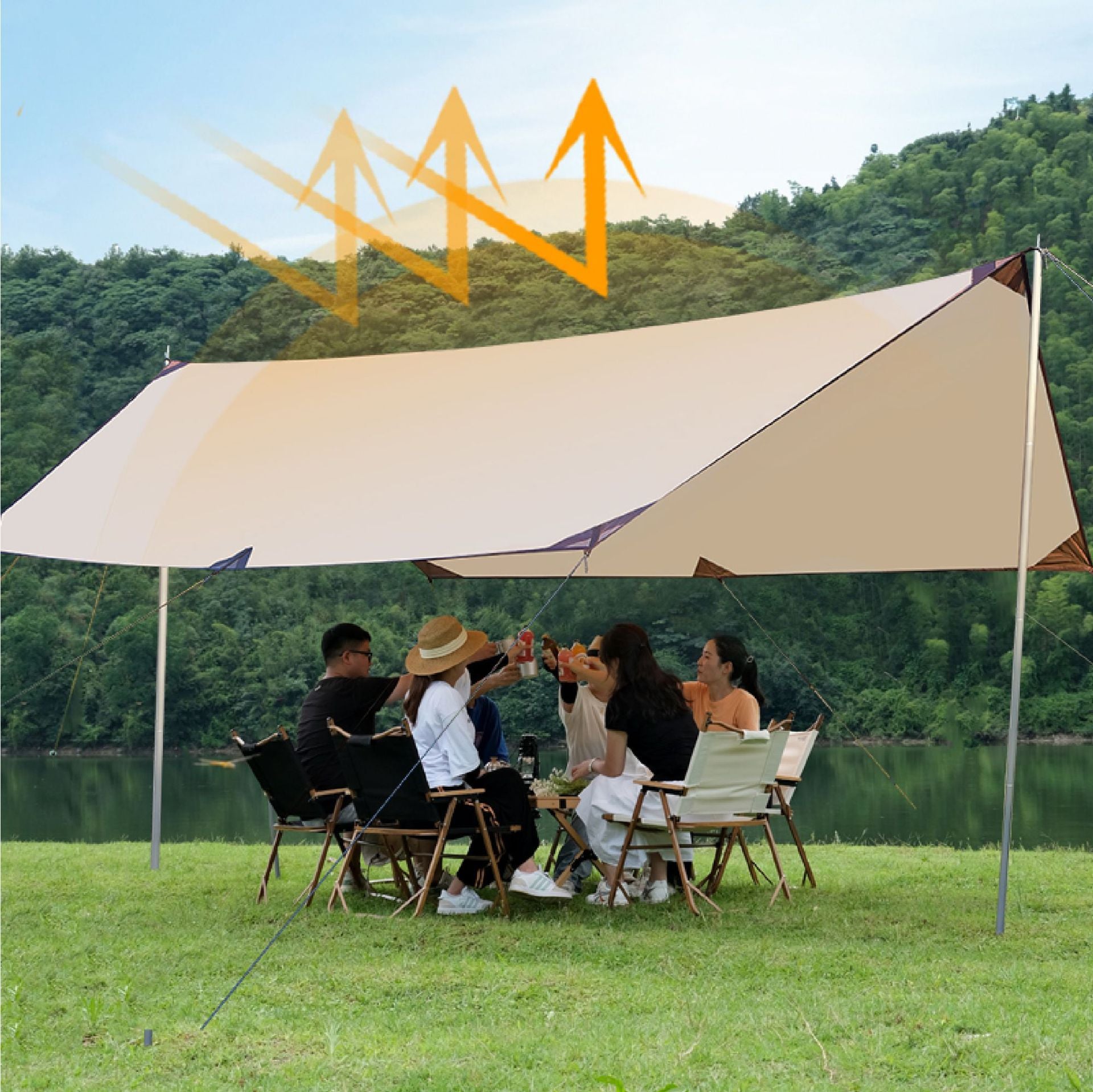 Group of people sitting under a large beige tent by a lake with mountains in the background.
