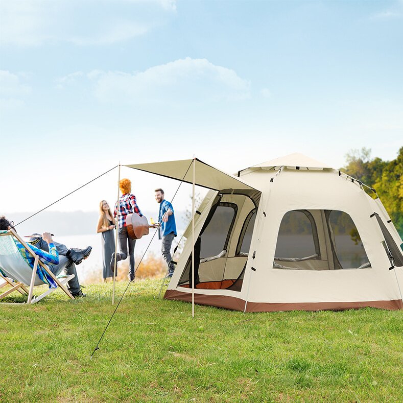 Group of people camping outdoors with a large tent on a grassy field.
