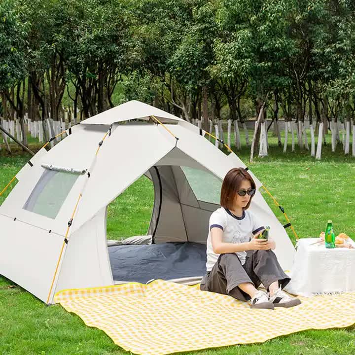 Person sitting outside a tent in a park-like setting