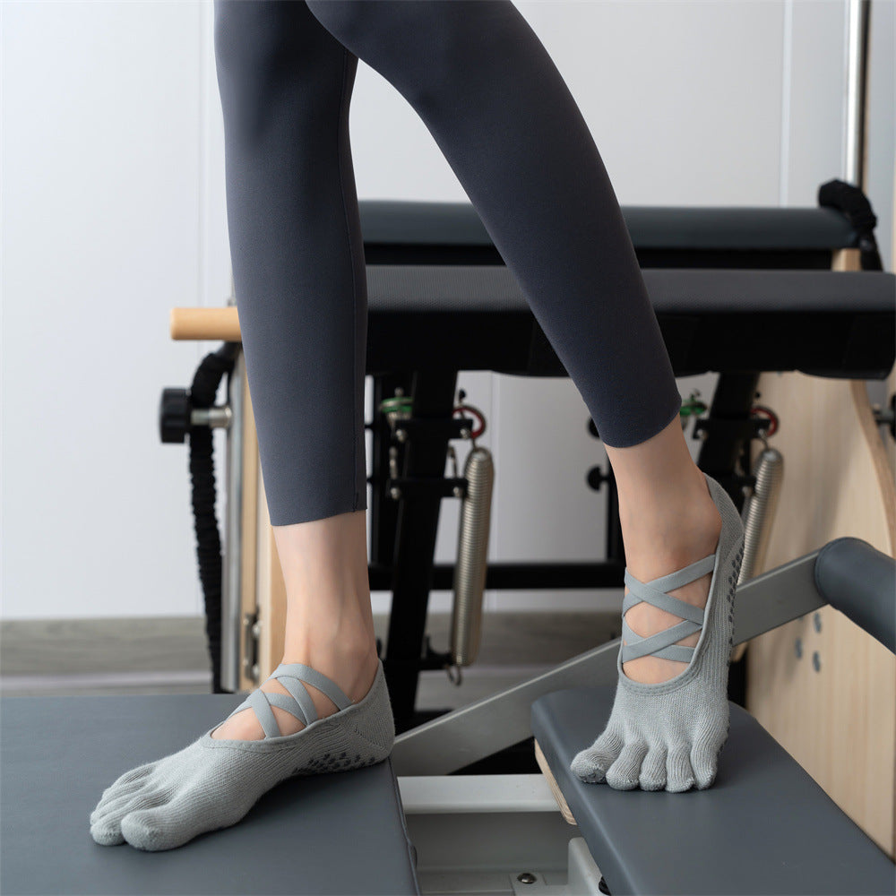 Person wearing gray toe-separated socks on a Pilates reformer machine.