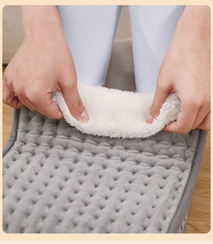 Gray quilted mat with white textured fabric being pulled apart by hands.
