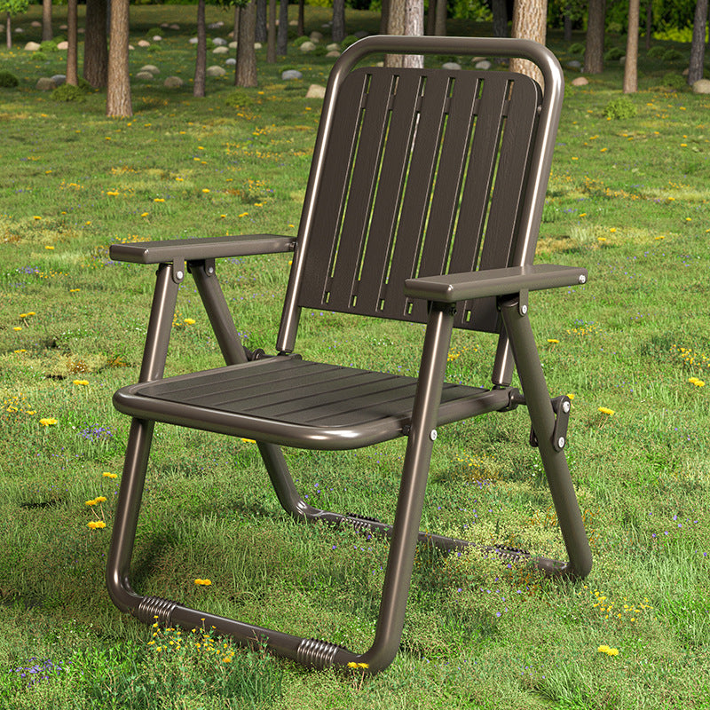 Brown folding chair on a grassy area with trees in the background
