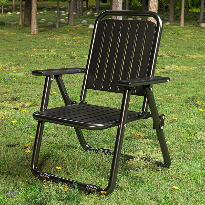 Black folding chair on a grassy area with trees in the background
