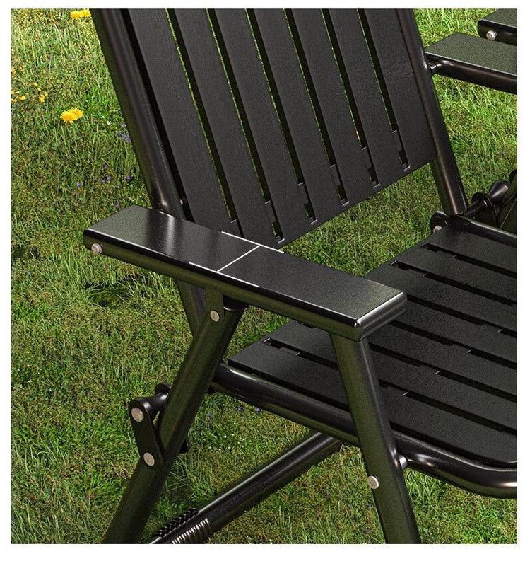 Black folding chair with armrest on a grassy background