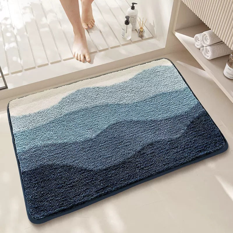 Blue gradient bath mat on a bathroom floor with a person stepping onto it.