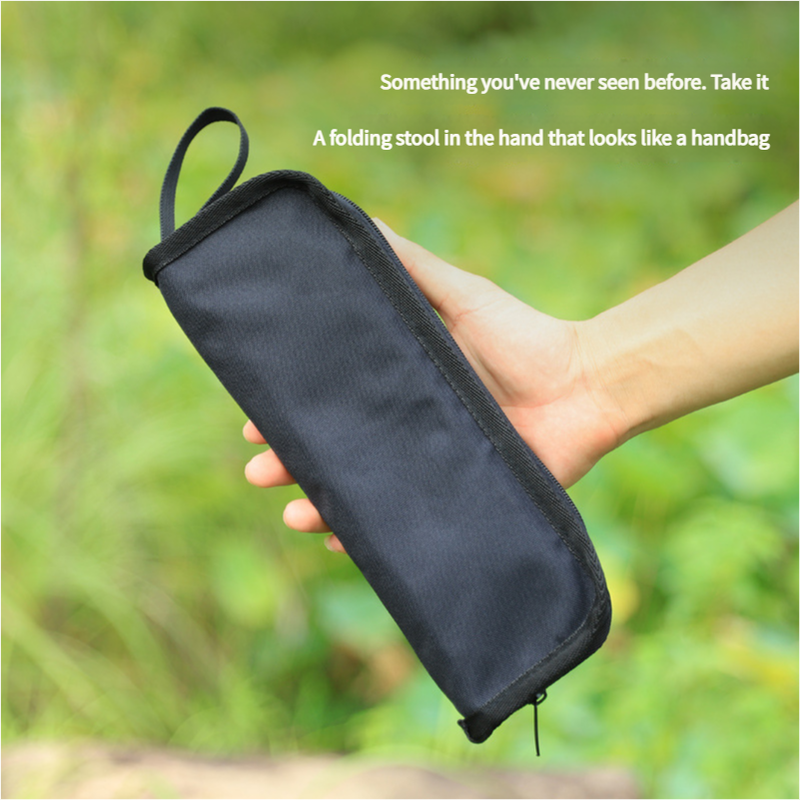 Black folding stool disguised as a handbag held in a hand with a green blurred background