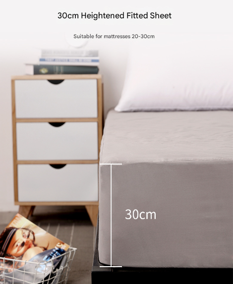 Gray fitted sheet on a bed with a nightstand and books in the background, labeled '30cm Heightened Fitted Sheet'.