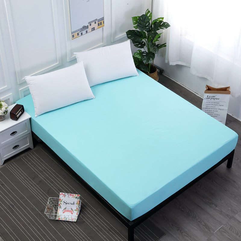 Bed with a light blue mattress cover and white pillows in a room with a plant and window.