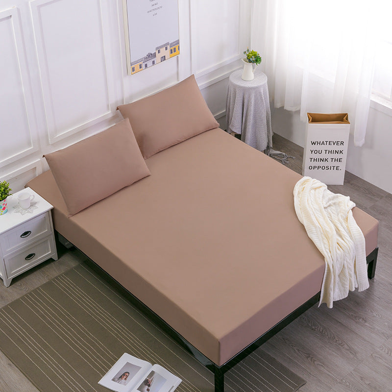 brown bedspread set on a bed in a room with a small table and decor items.