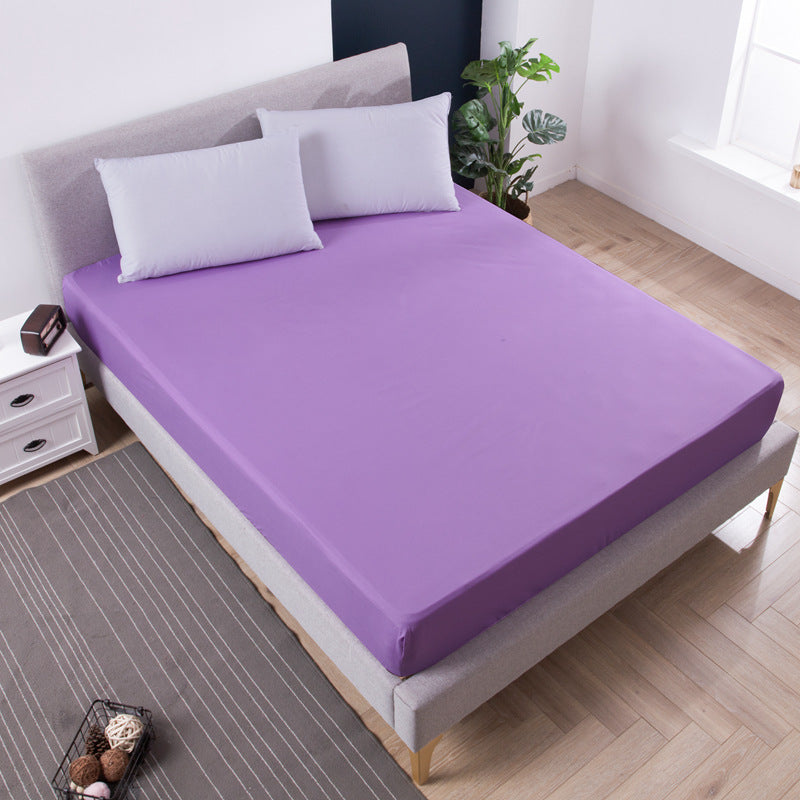 Purple bed sheet on a bed in a bedroom setting with pillows and a plant.