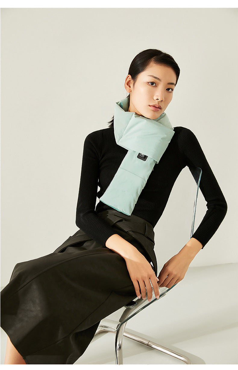 Woman wearing a light blue scarf and black outfit sitting on a chair against a white background