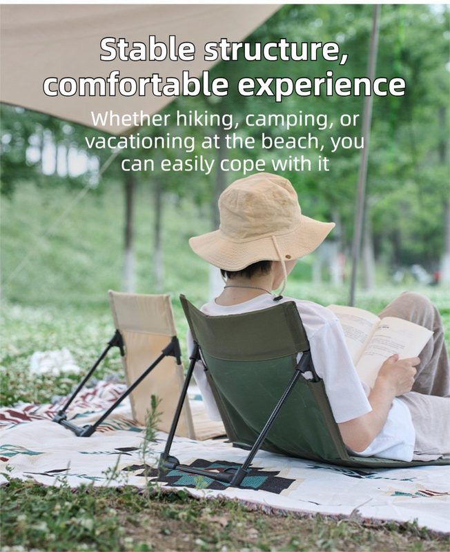 Person sitting on a green camping chair with a hat, reading a book, surrounded by nature.