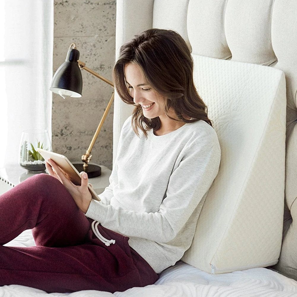 Woman sitting on a bed using a tablet in a bright bedroom.