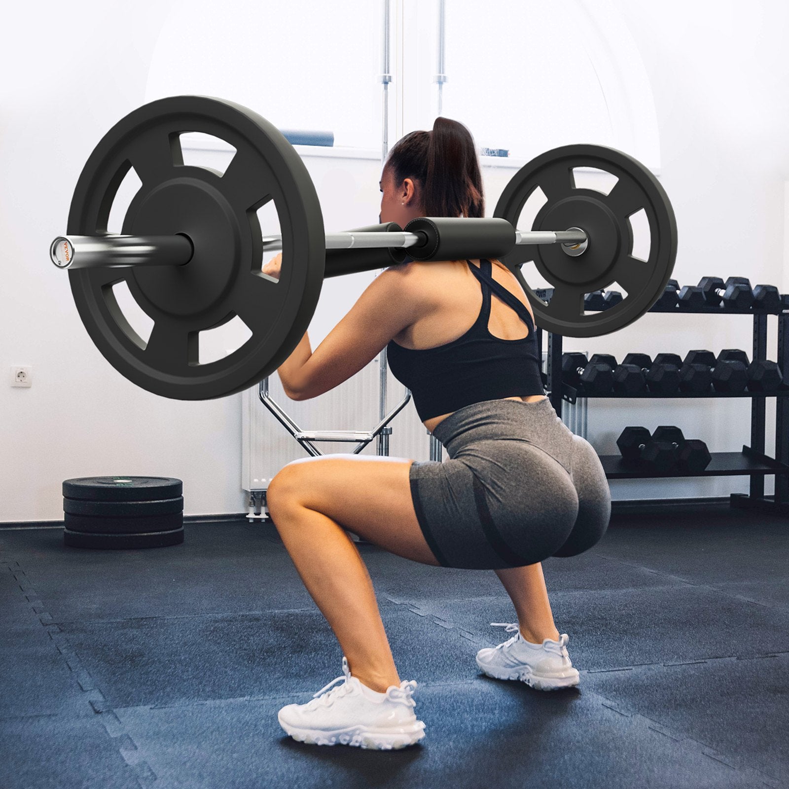 Woman performing squats with a barbell in a gym setting