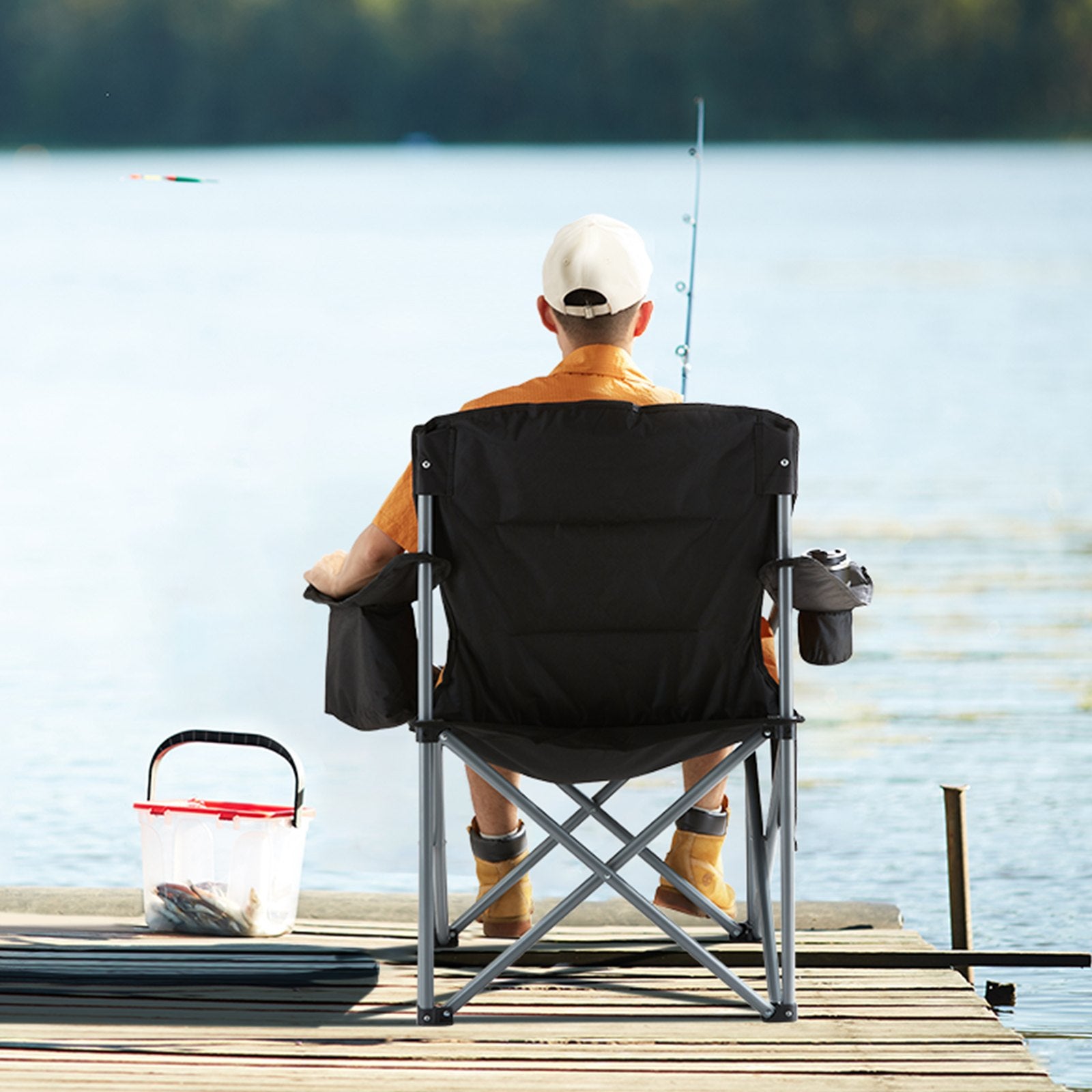 Man sitting in a black folding chair on a dock, fishing.
