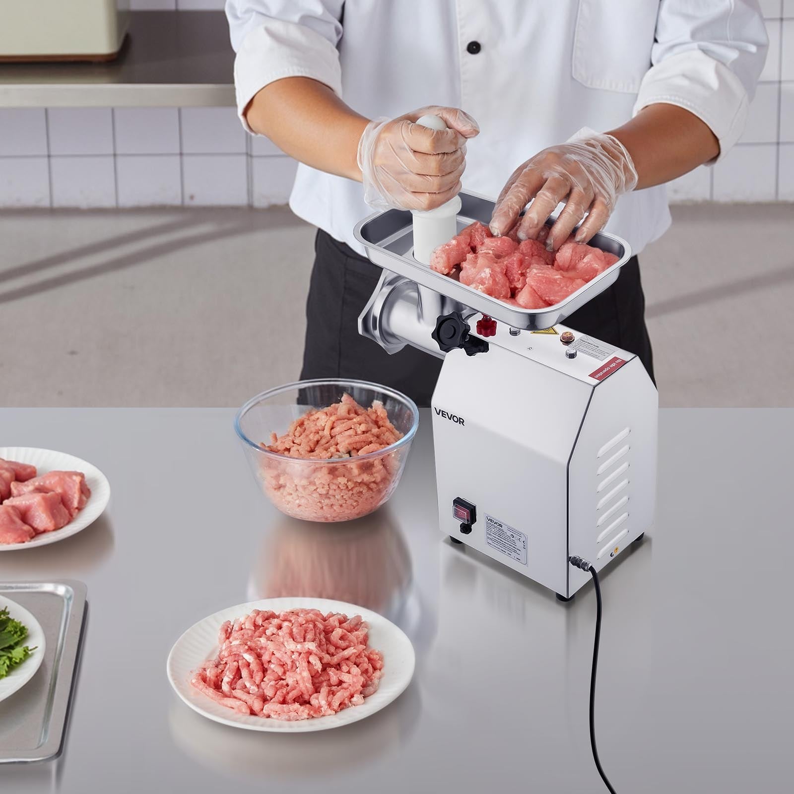 Person using a meat grinder to make ground meat in a kitchen setting.