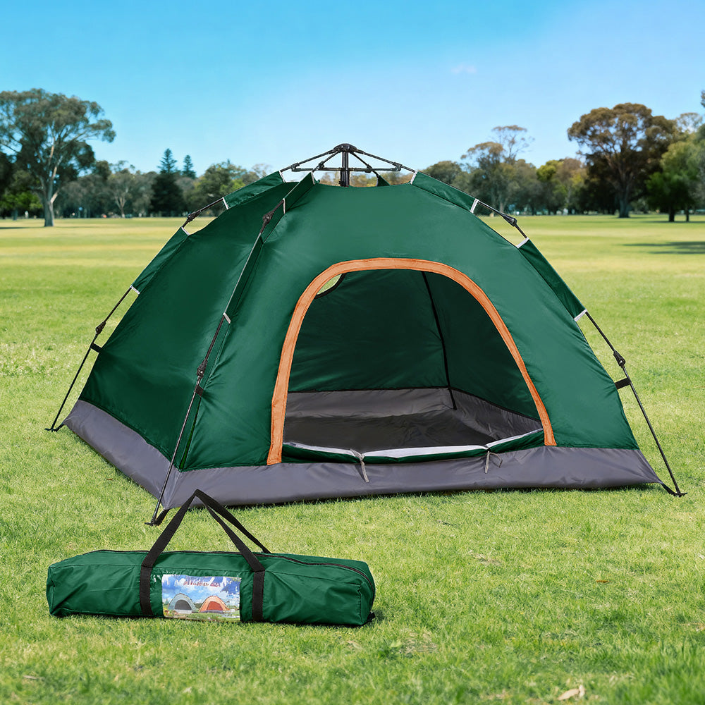 Green camping tent with carrying bag on grassy field